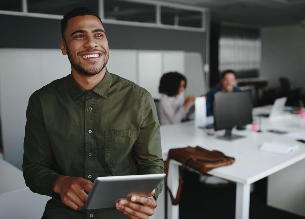 A smiling business owner holds a tablet.