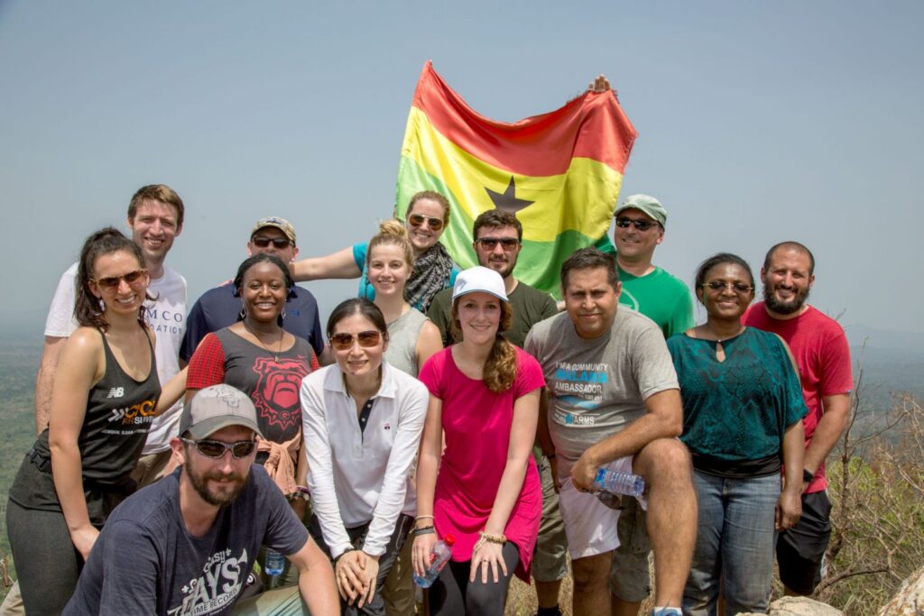 A group of volunteers holds up a flag of Ghana