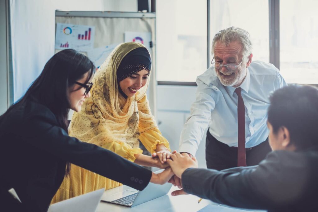 Four people form a huddle in a conference room