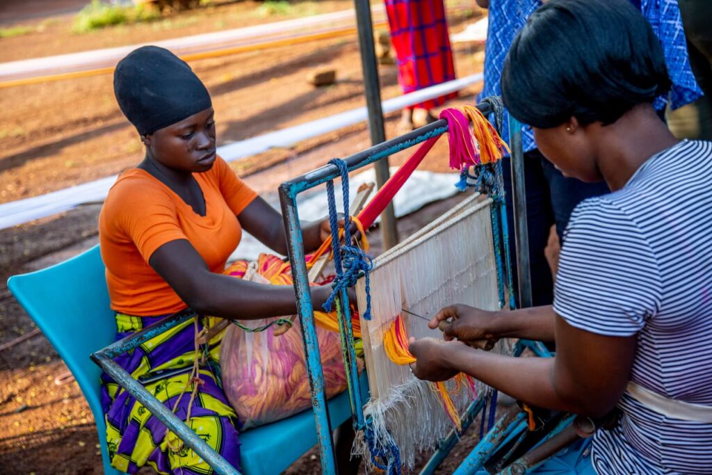 Two women weaving a rug.