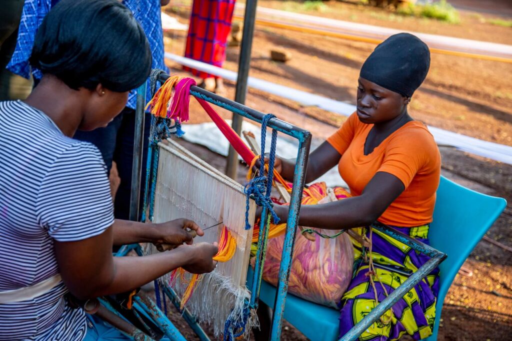 Two women weaving a rug.